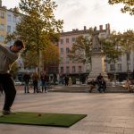 Street golf à Lyon : joueur en swing sur une place lyonnaise